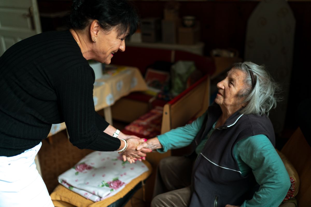 A caregiver warmly greeting an older adult at home